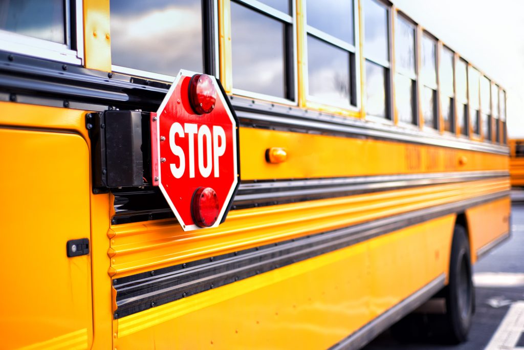 Close up of a yellow school bus with the red STOP sign